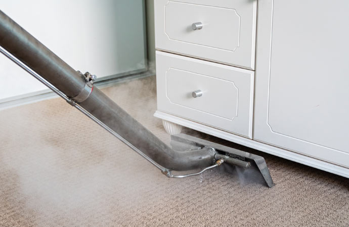 Steam cleaning bedroom carpets for a refreshed look.