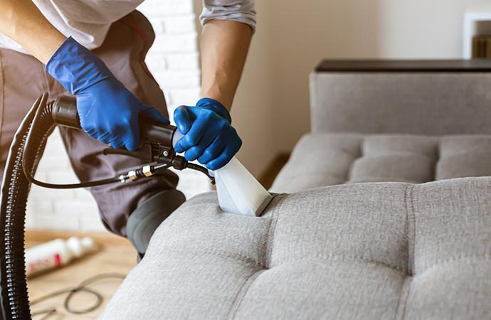 worker cleaning sofa in Baltimore